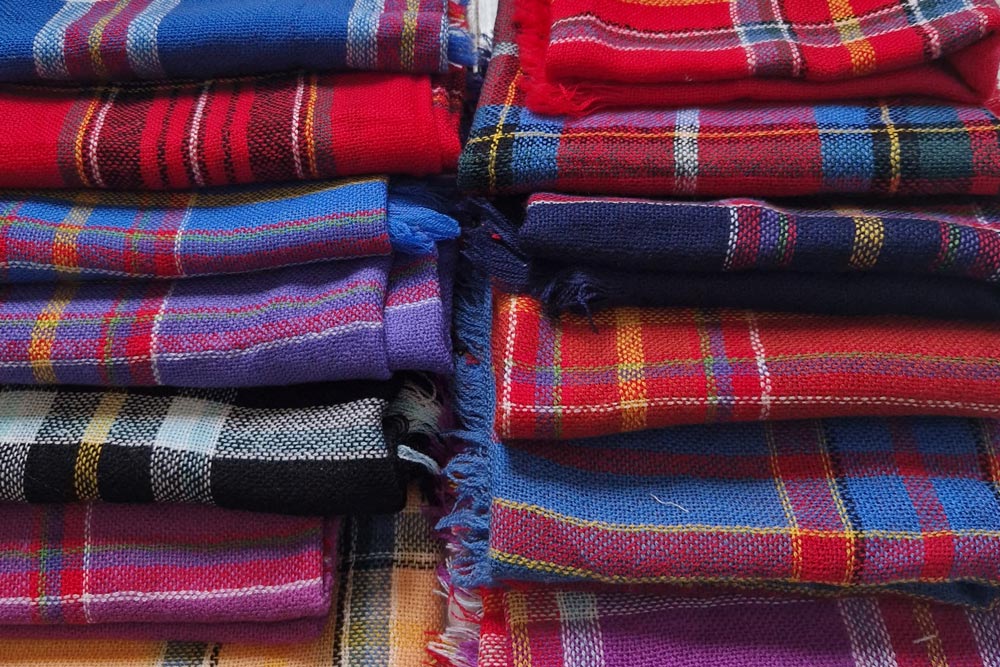 Flera sami sjalar i olika färger vikta i en hög